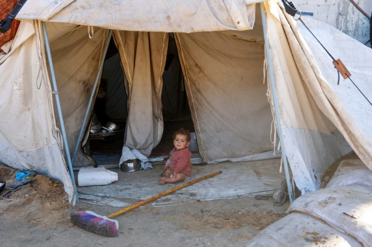 صوره – طفل فلسطيني نازح يجلس أمام خيمة النزوح التي نصبت مع مئات خيام اللجوء المؤقتة في غزة.