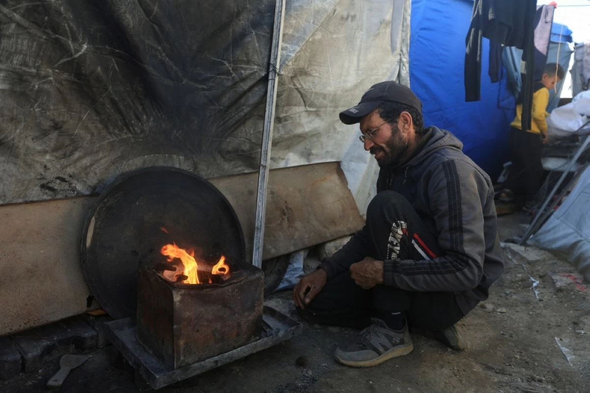كاريكاتير – فلسطيني نازح يشعل النار للتدفئة بالقرب من خيمته المؤقتة شرق مدينة غزة. (رويترز)
