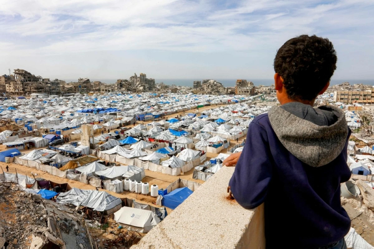 صوره – طفل فلسطيني ينظر إلى الخيام التي يأوي فيها النازحون الفلسطينيون التي تم نصبها بجوار المباني المدمرة والمتضررة بشدة في منطقة المواصي بمدينة غزة. (فرانس برس)