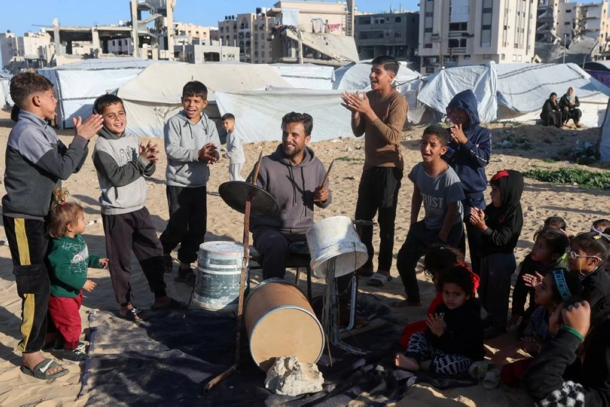 صوره – عازف الطبول الفلسطيني حسام قاسم يعزف على الطبول محلية الصنع لتسلية الأطفال في مخيم خان يونس جنوب قطاع غزة.