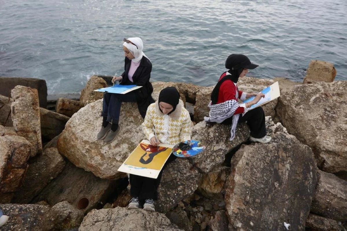 صوره – فنانون فلسطينيون يرسمون في ميناء مدينة غزة ضمن ورشة “تنفس وارسم” للفتيات في غزة. (فرانس برس)