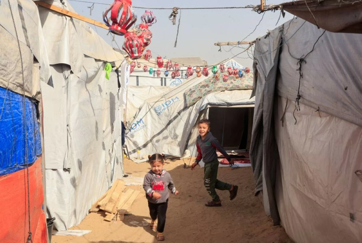 صوره – طفلان فلسطينيان يلعبان بين خيم مزينة بفوانيس رمضان المصنوعة يدويا في خان يونس جنوب قطاع غزة.