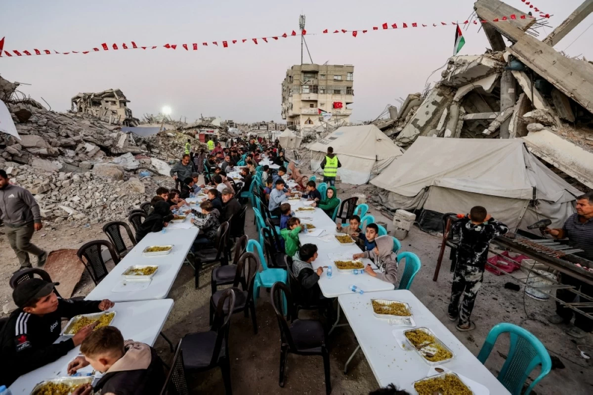 صوره – فلسطينيون يتجمعون على طاولات إفطار جماعية أمام منازلهم المدمرة في مدينة غزة.
