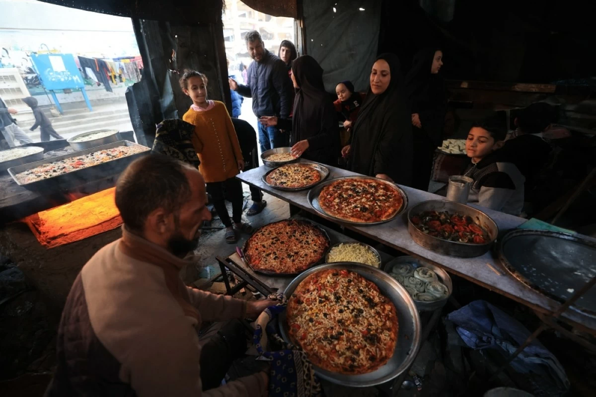 صوره – عائلة فلسطينية نازحة تقوم بإعداد وجبة الإفطار خلال شهر رمضان المبارك، وسط الدمار الذي لحق بمخيم البريج للاجئين وسط قطاع غزة.
