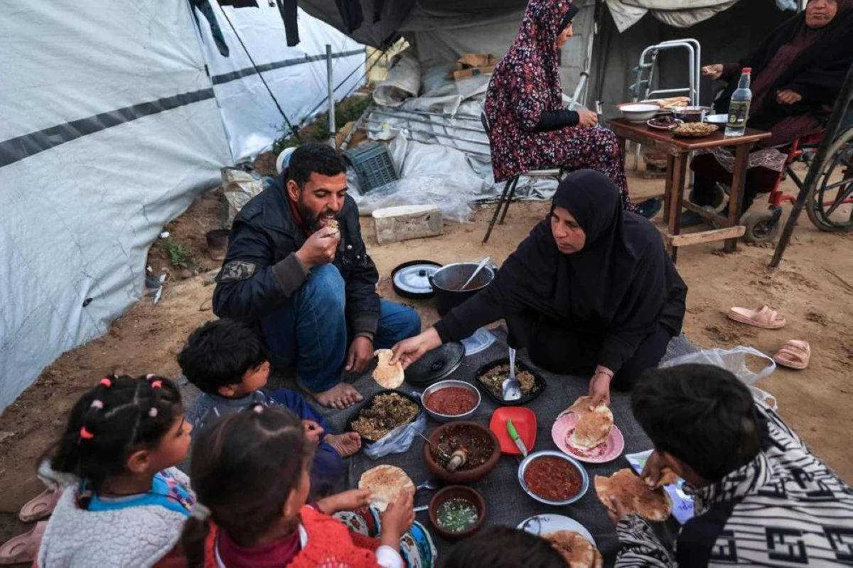 صوره – عائلة فلسطينية نازحة تتناول وجبة الإفطار في مخيم النصيرات للاجئين وسط قطاع غزة. (فرانس برس)