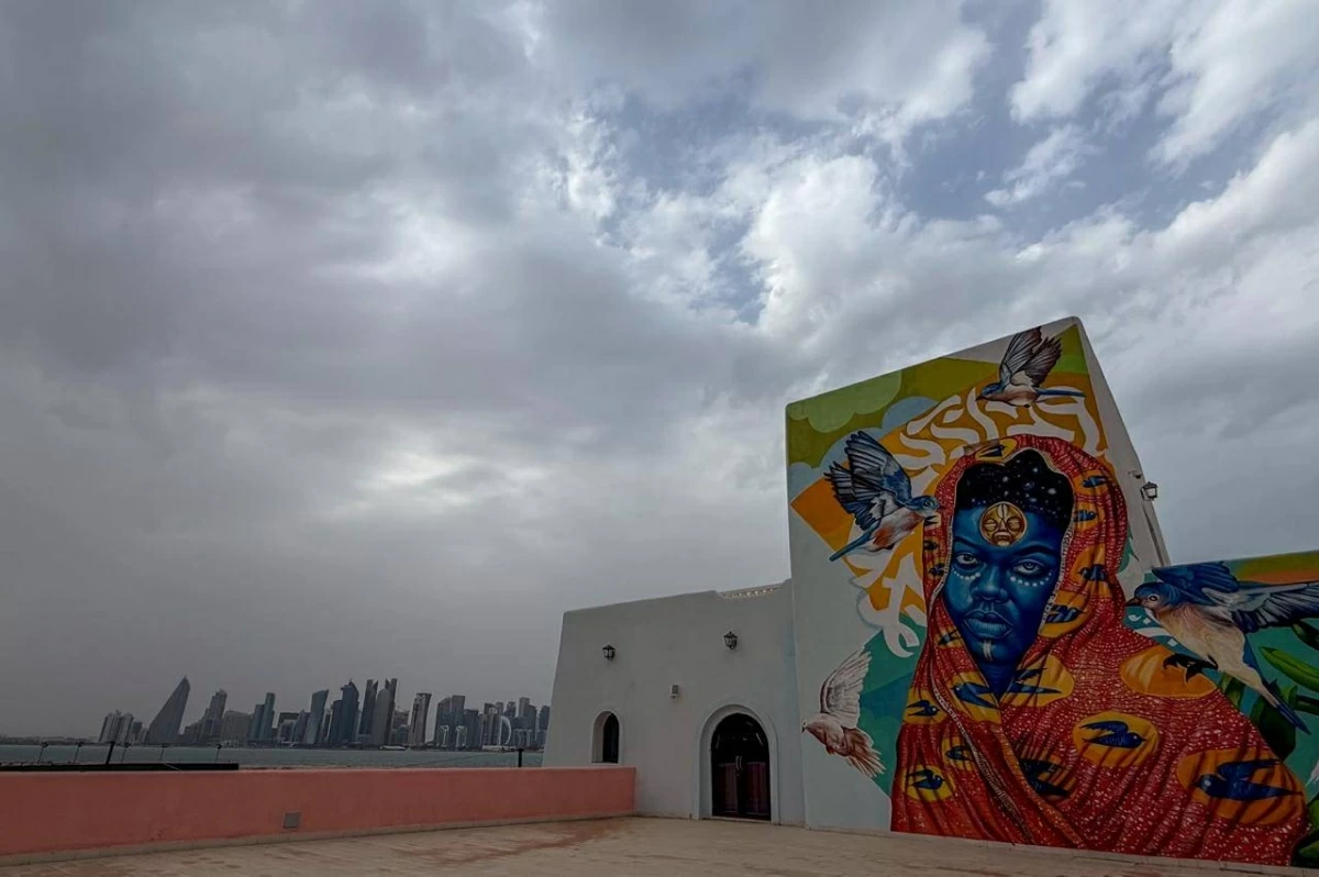صوره – رسومات جرافيتي على المباني في ميناء الدوحة القديم، مع ظهور الأبراج في الخلفية.