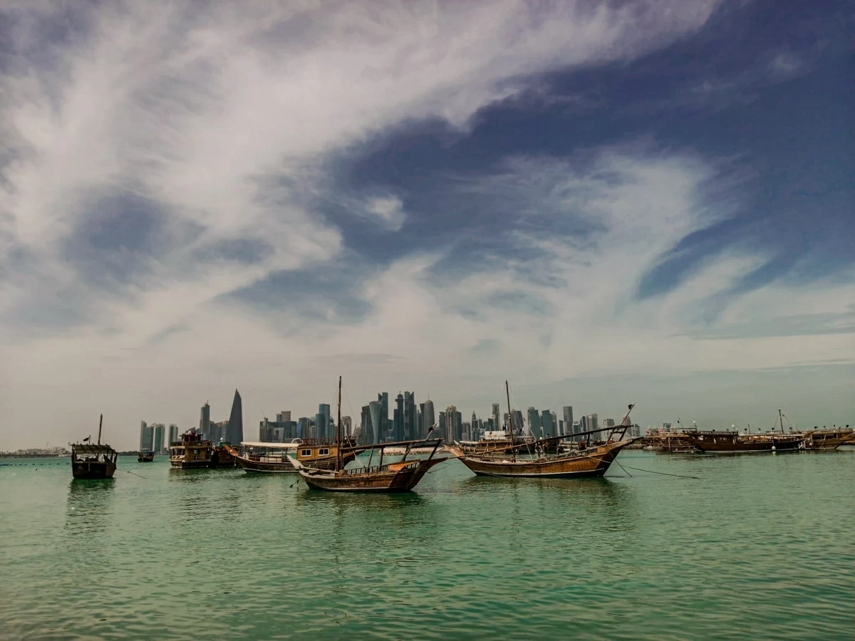 صوره – محامل خشبية تطفو فوق مياه الخليج على كورنيش الدوحة، وتظهر منطقة الأبراج في الخلفية.